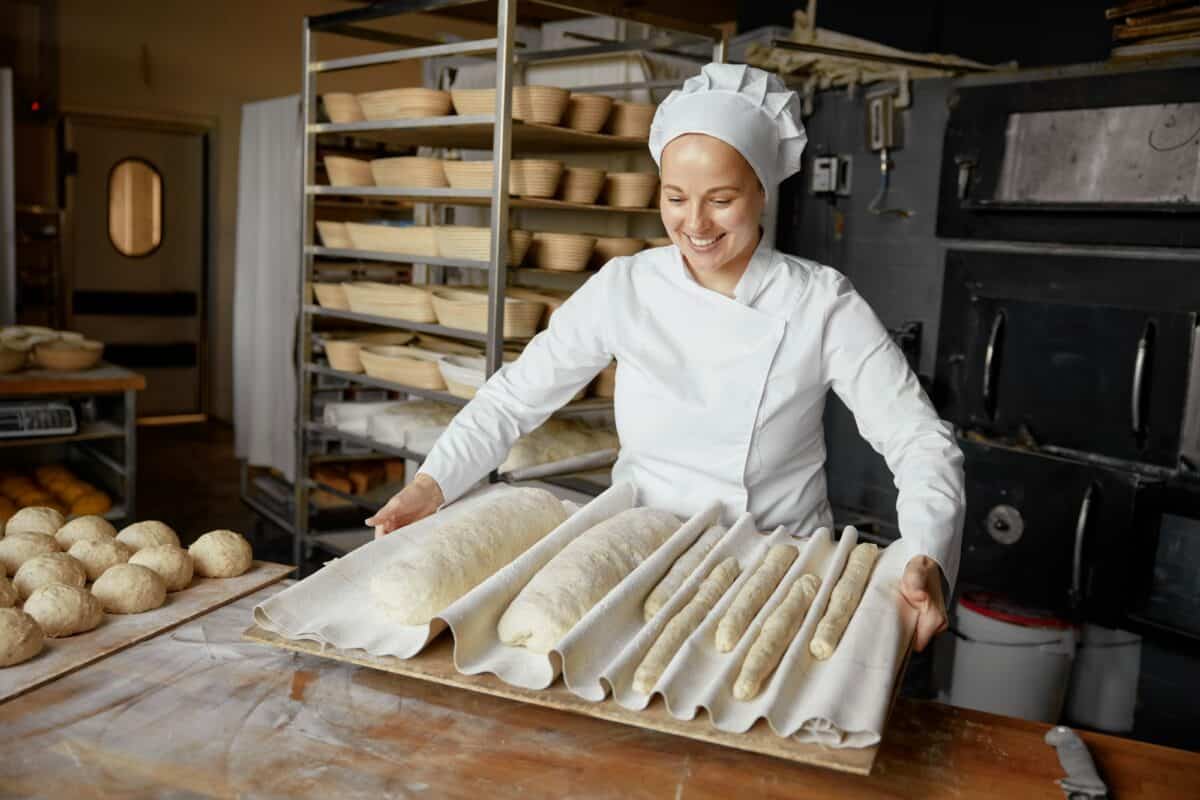 Femme boulangère ou pâtissière fabriquant du pain frais dans une boulangerie locale