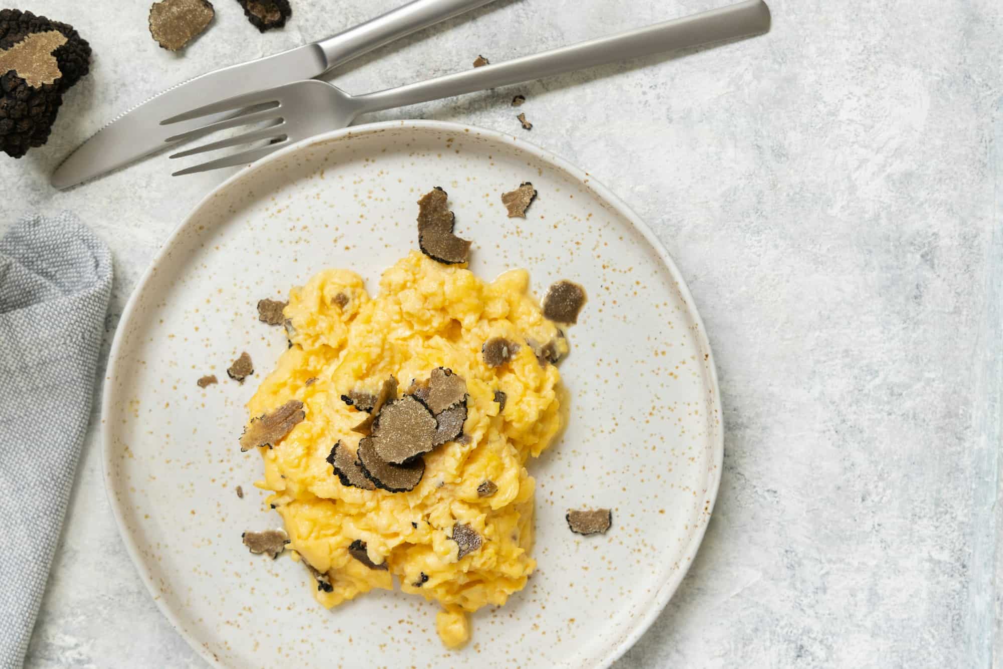 Œufs brouillés aux truffes noires fraîches d'Italie servis dans une assiette vue du dessus, petit déjeuner gourmet